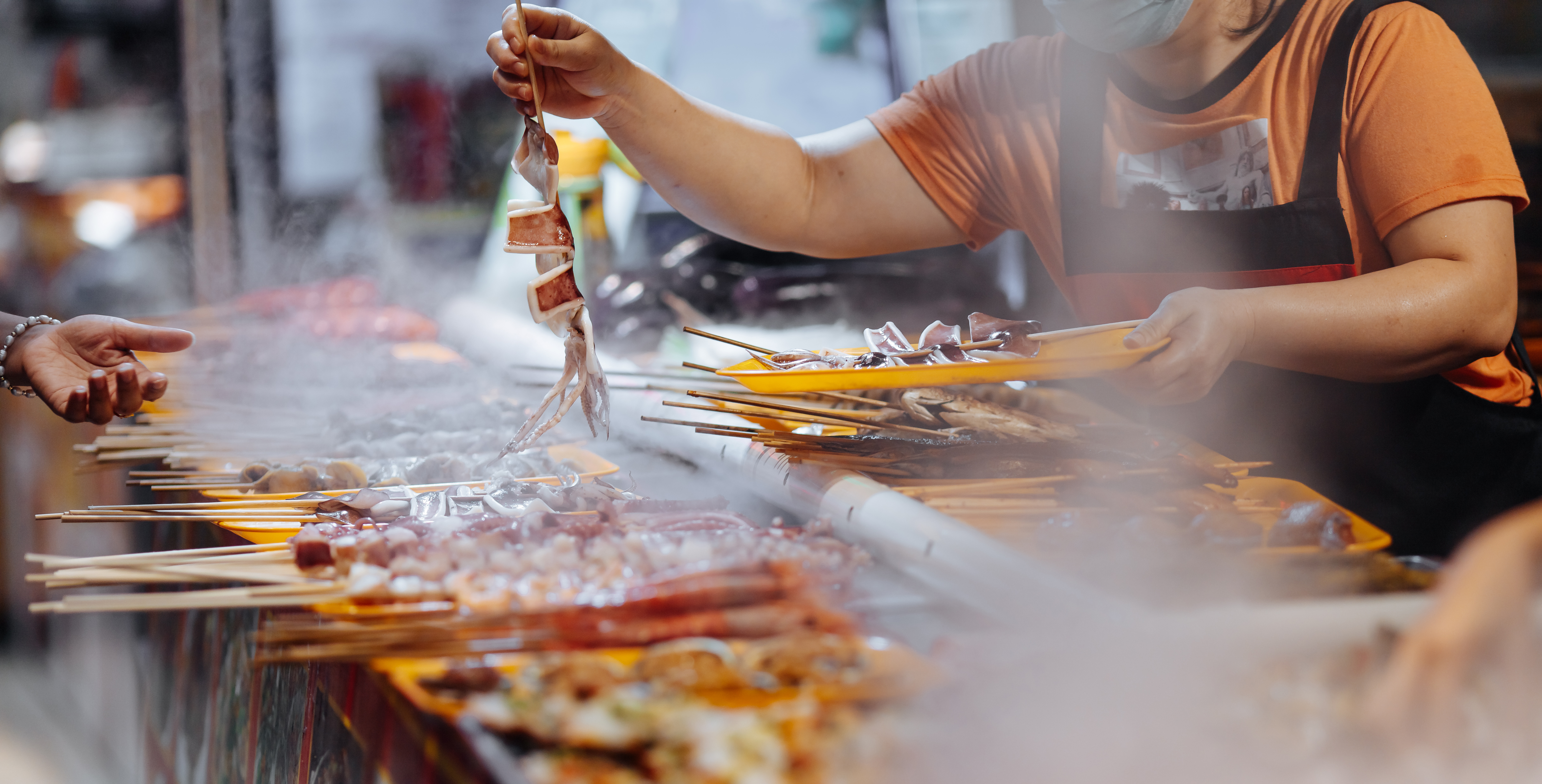 Large variety of delicious grilled seafood on wooden skewers. Street Food market with fresh meal for tourists. Traditional asian cuisine concept.
